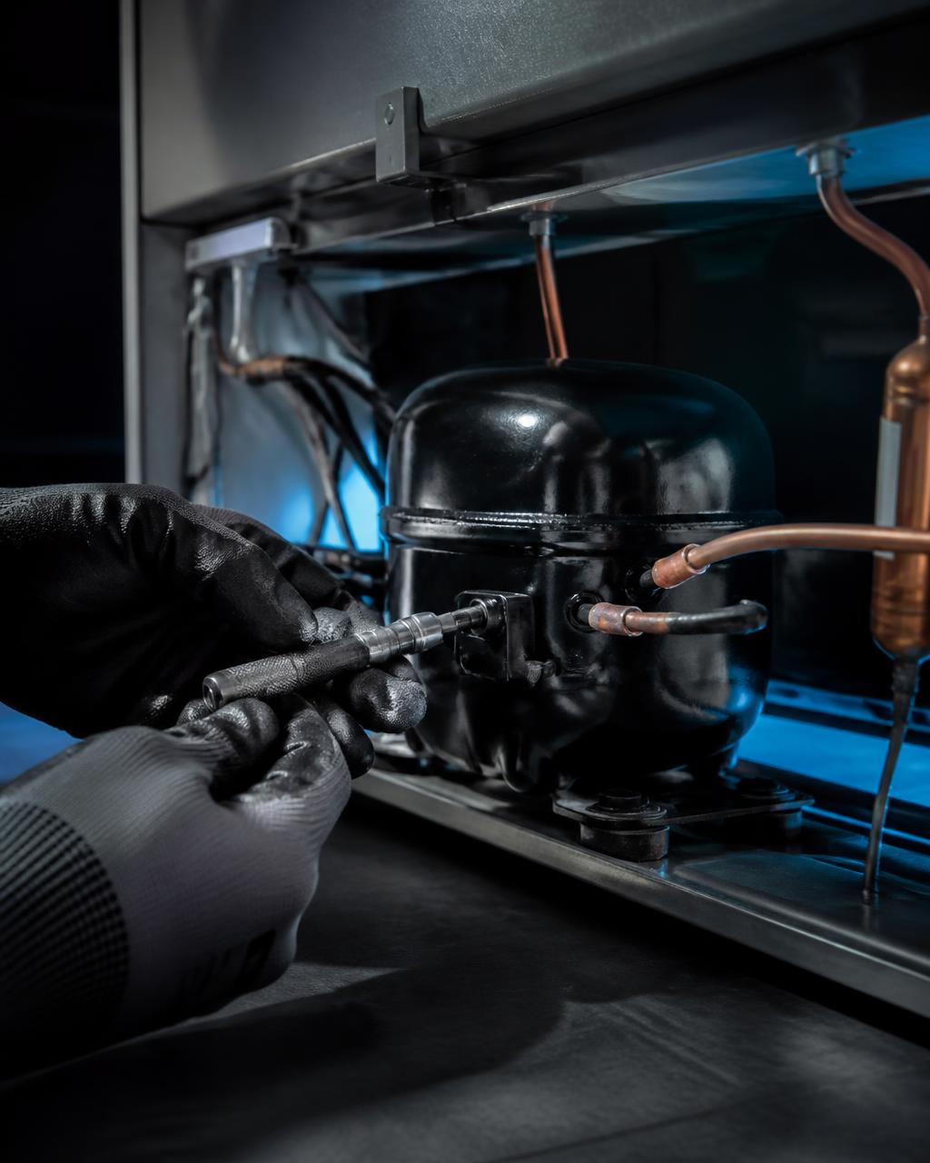 Detalhe do compressor de um freezer durante conserto especializado